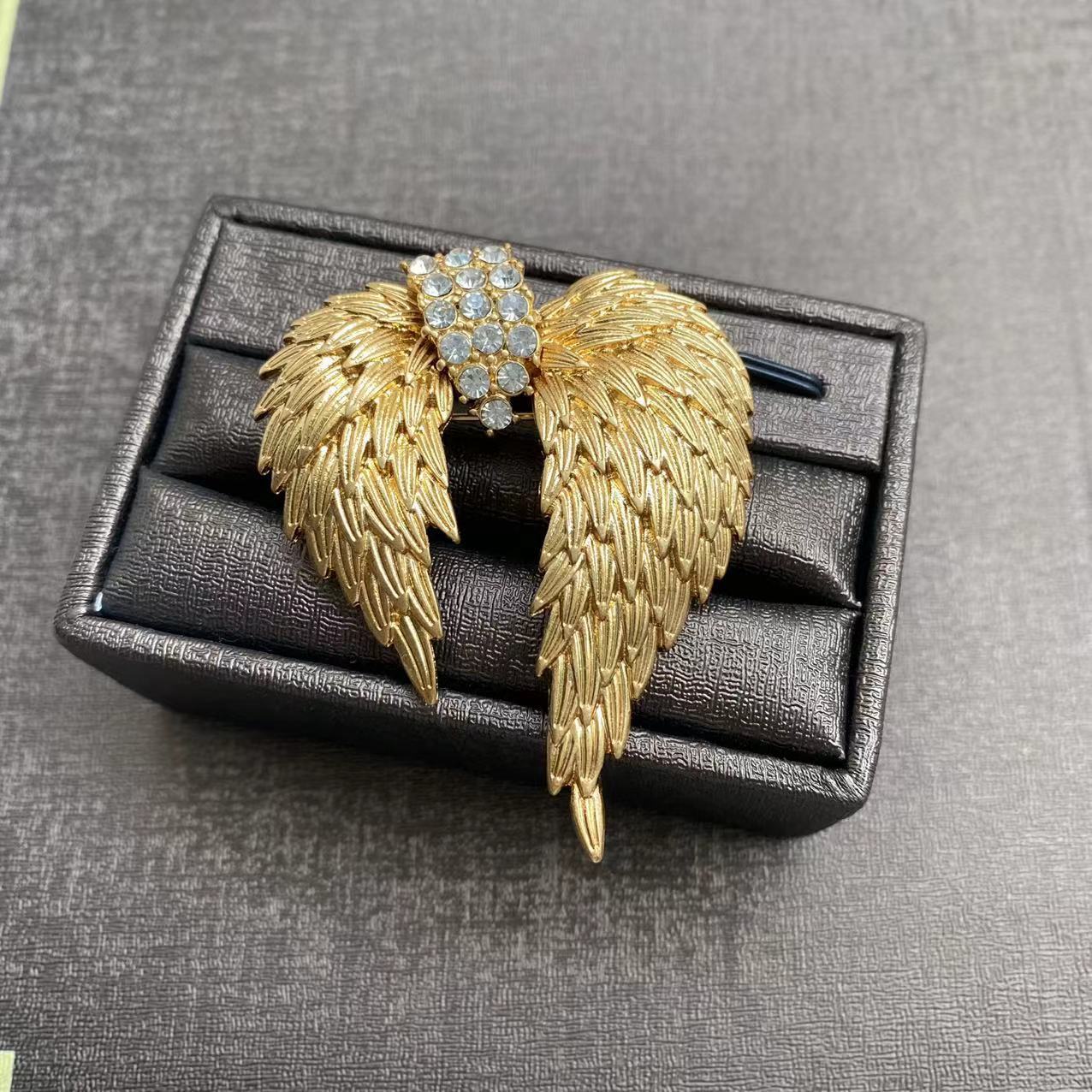 Elegant gold plated angel wing brooch featuring shimmering white cubic zirconia stones in a detailed feather design