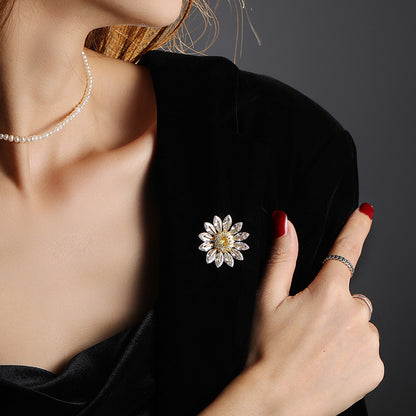Charming gold plated daisy brooch featuring white cubic zirconia petals and a bright yellow stamen center