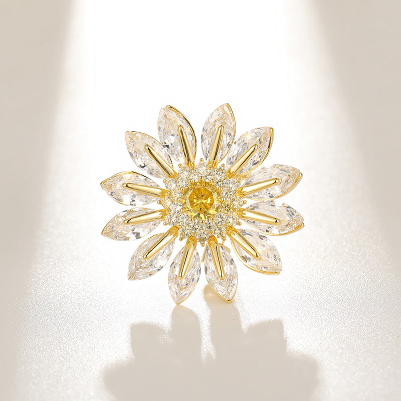 Charming gold plated daisy brooch featuring white cubic zirconia petals and a bright yellow stamen center