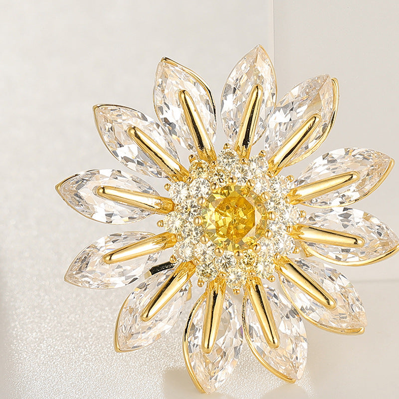 Charming gold plated daisy brooch featuring white cubic zirconia petals and a bright yellow stamen center