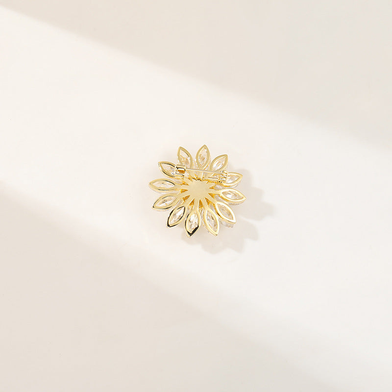 Charming gold plated daisy brooch featuring white cubic zirconia petals and a bright yellow stamen center