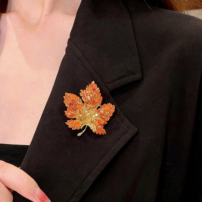 Elegant gold plated maple leaf brooch featuring gradient red cubic zirconia stones in a seasonal autumn design