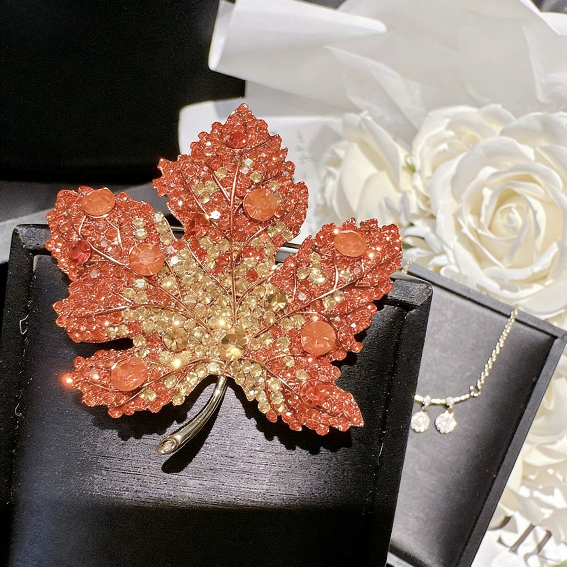 Elegant gold plated maple leaf brooch featuring gradient red cubic zirconia stones in a seasonal autumn design