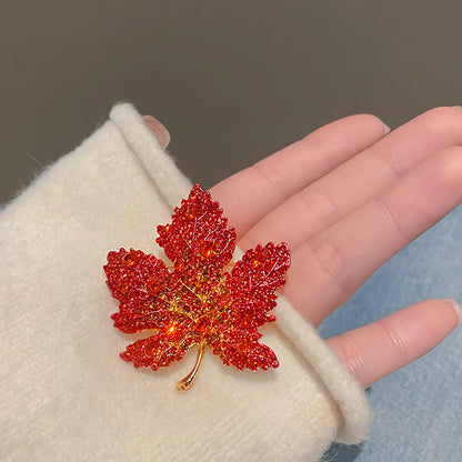 Elegant gold plated maple leaf brooch featuring gradient red cubic zirconia stones in a seasonal autumn design
