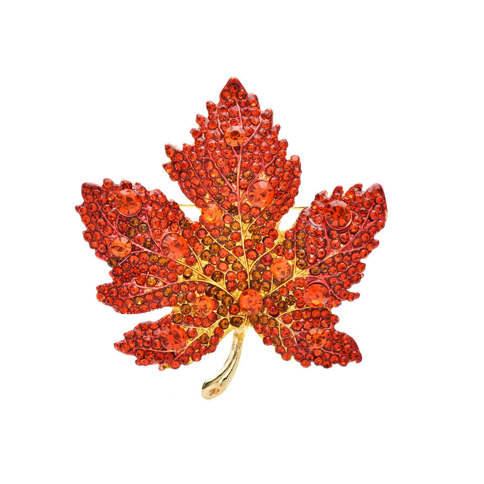 Elegant gold plated maple leaf brooch featuring gradient red cubic zirconia stones in a seasonal autumn design