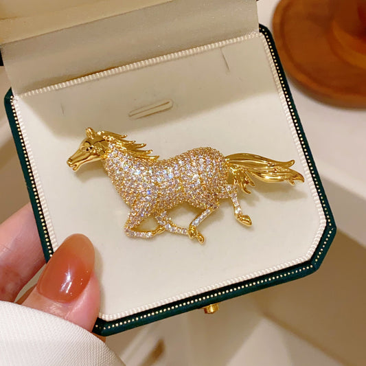 Golden running horse brooch featuring sparkling white cubic zirconia stones in a detailed animal-inspired design