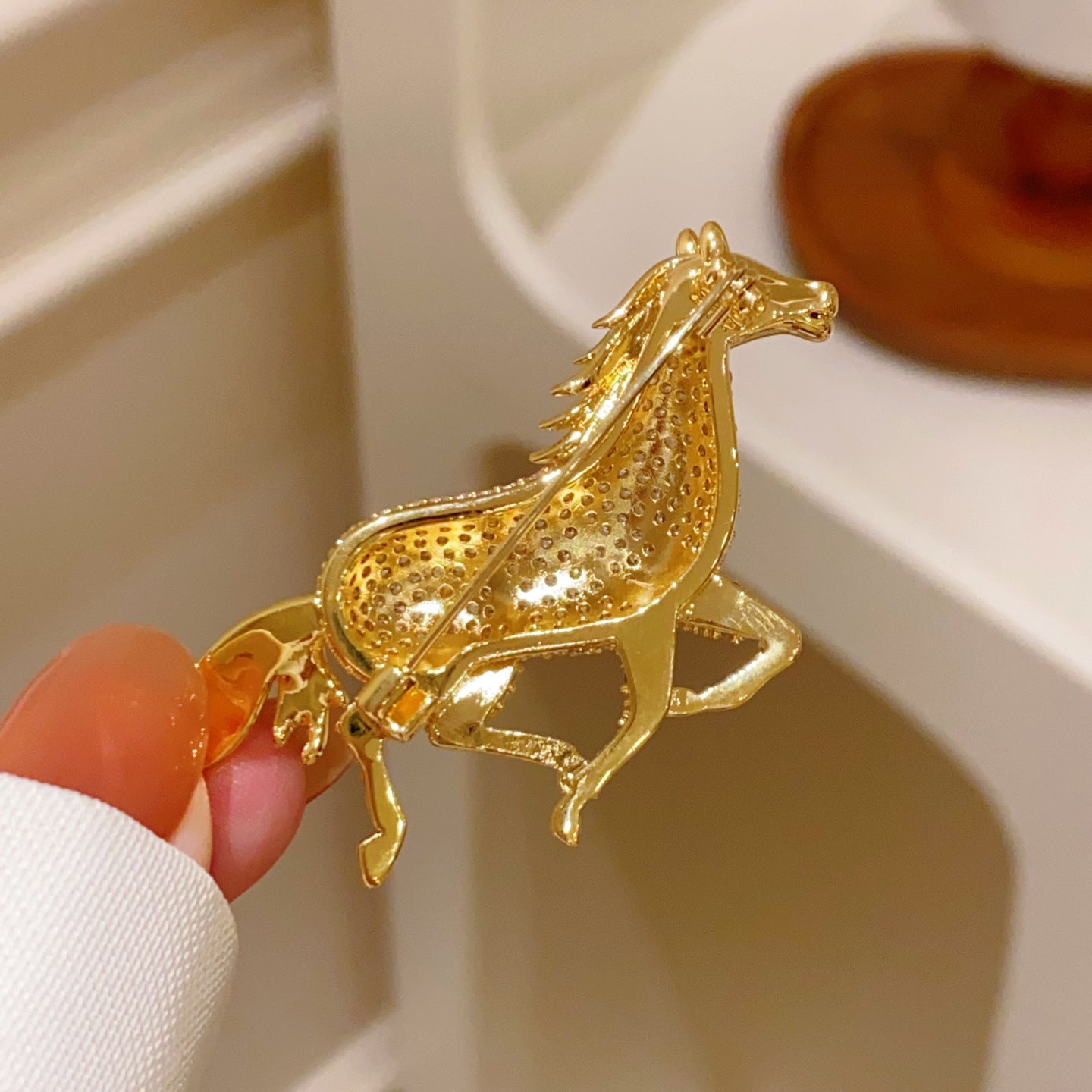 Golden running horse brooch featuring sparkling white cubic zirconia stones in a detailed animal-inspired design