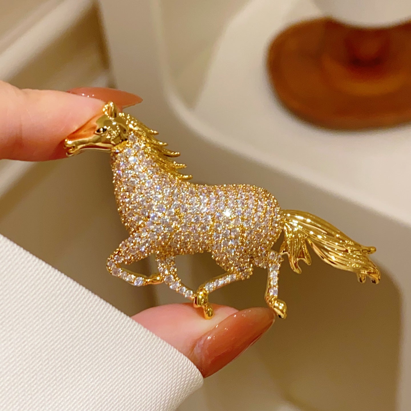 Golden running horse brooch featuring sparkling white cubic zirconia stones in a detailed animal-inspired design