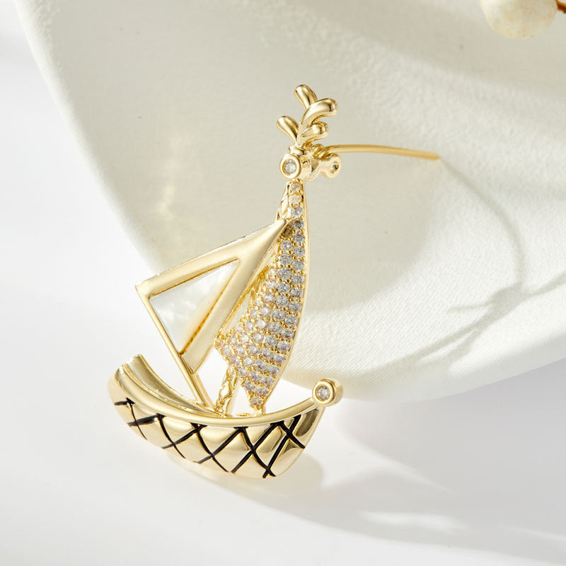 Elegant gold plated sailboat brooch featuring shimmering white cubic zirconia sails in a nautical-inspired design