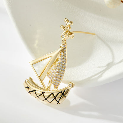 Elegant gold plated sailboat brooch featuring shimmering white cubic zirconia sails in a nautical-inspired design