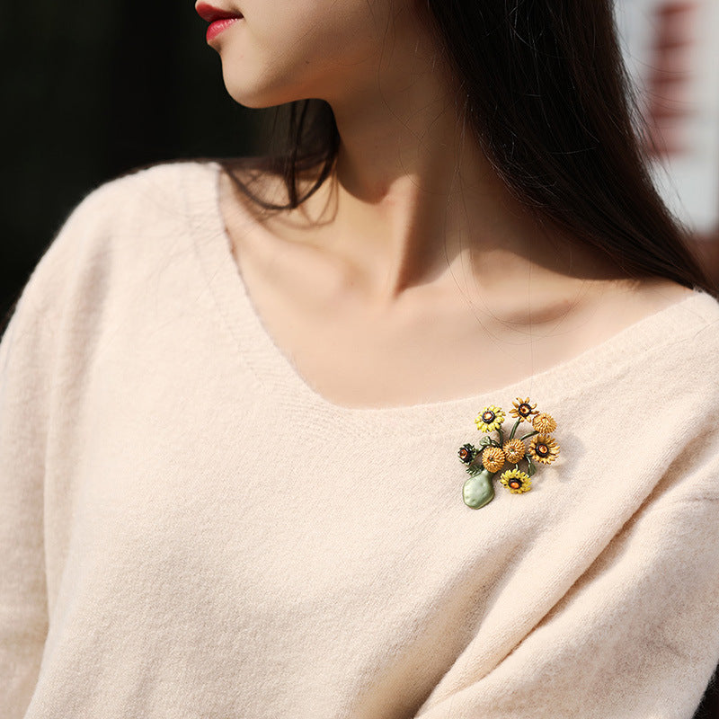 Vintage-style gold-plated sunflower brooch featuring vibrant yellow enamel petals and a textured floral design