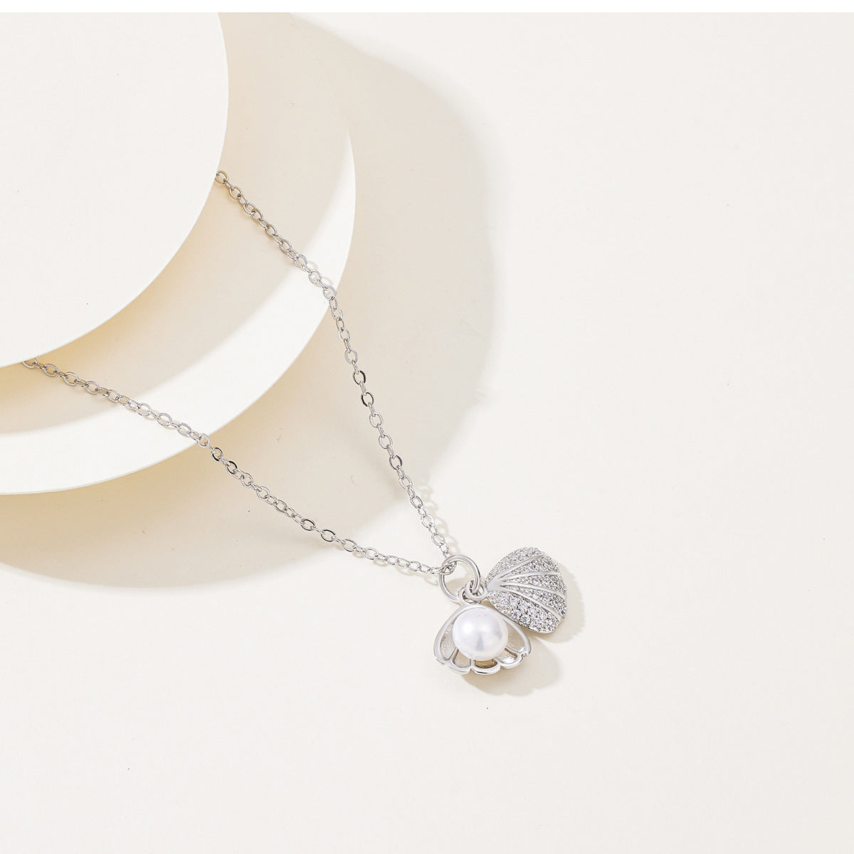 Elegant gold  silver necklace featuring a shell-shaped pendant with a central pearl and shimmering zircon stones on the outer rim