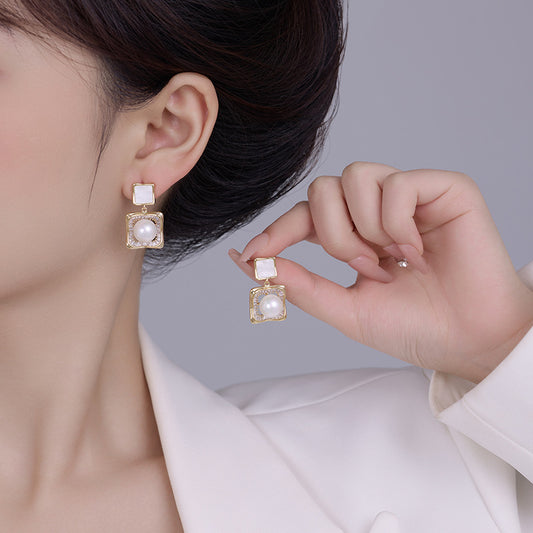 Elegant square zirconia stud earrings with a dangling white pearl charm, available in gold and silver finishe