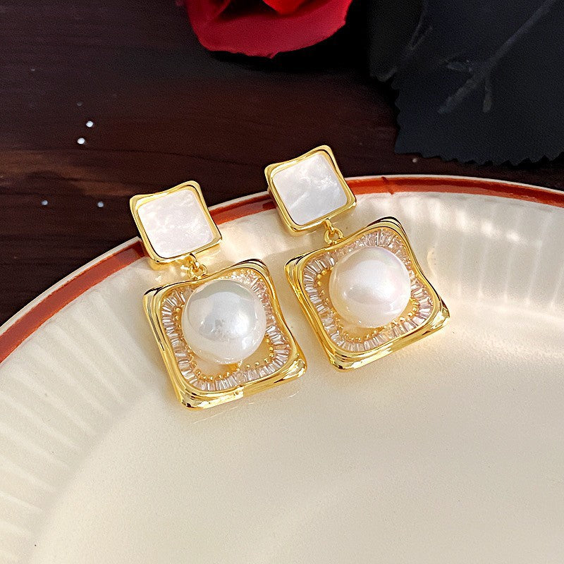 Elegant square zirconia stud earrings with a dangling white pearl charm, available in gold and silver finishe