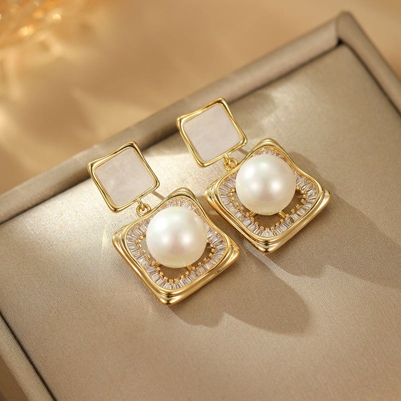 Elegant square zirconia stud earrings with a dangling white pearl charm, available in gold and silver finishe