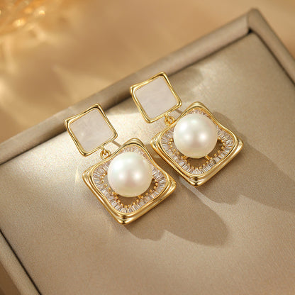 Elegant square zirconia stud earrings with a dangling white pearl charm, available in gold and silver finishe