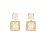 Elegant square zirconia stud earrings with a dangling white pearl charm, available in gold and silver finishe