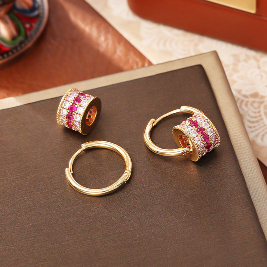 Gold triple-layer cylinder earrings featuring rows of sparkling pink cubic zirconia in a bold, modern hoop design