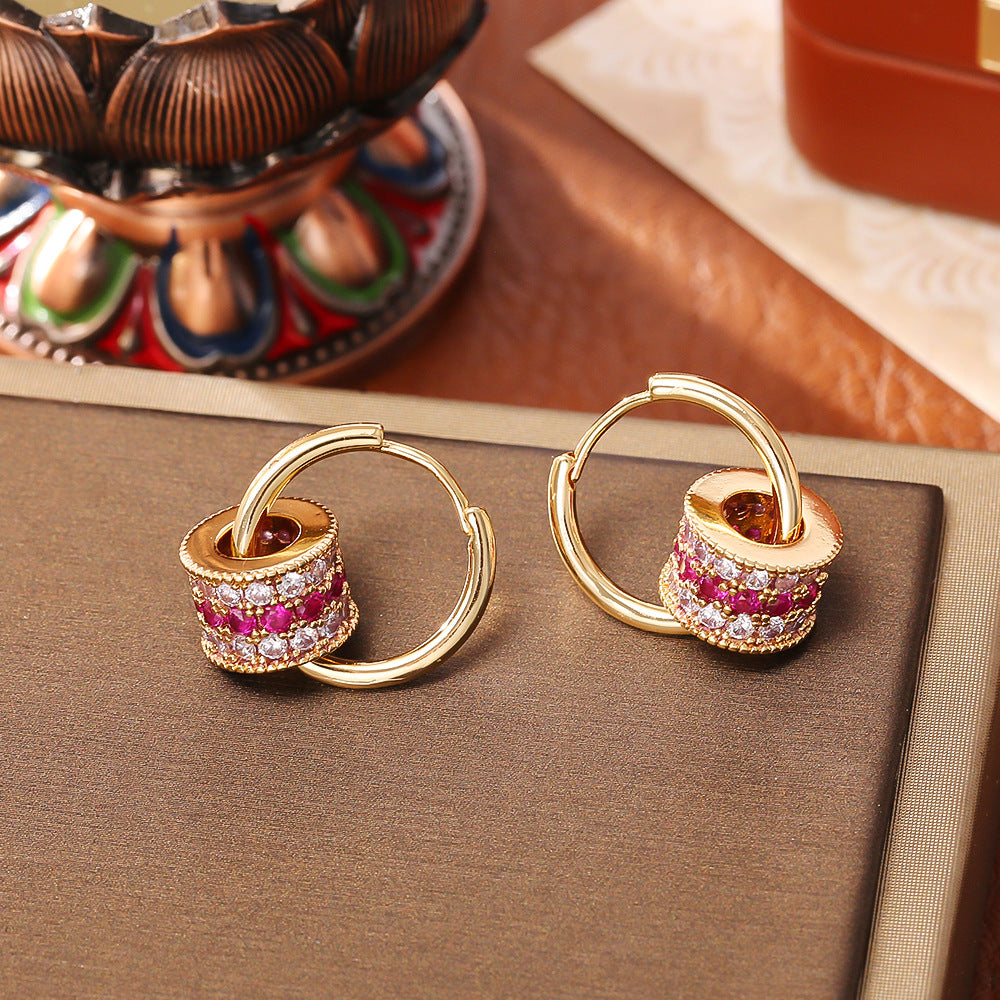 Gold triple-layer cylinder earrings featuring rows of sparkling pink cubic zirconia in a bold, modern hoop design