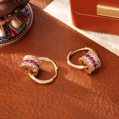 Gold triple-layer cylinder earrings featuring rows of sparkling pink cubic zirconia in a bold, modern hoop design