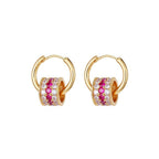 Gold triple-layer cylinder earrings featuring rows of sparkling pink cubic zirconia in a bold, modern hoop design