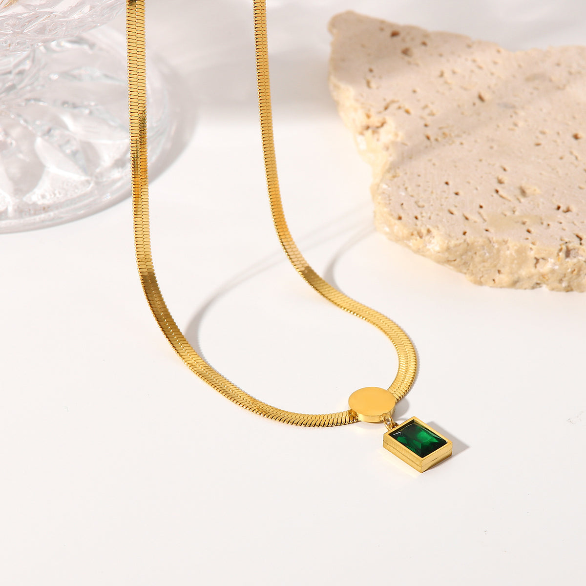 Emerald cut green cubic zirconia cz crystal bezel pendant on flat herringbone snake chain necklace stainless steel jewelry in waterproof 18k gold plated finish.