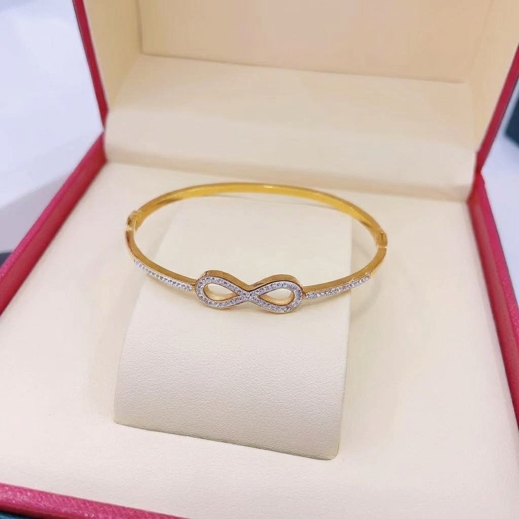 Infinity loop motif pave cubic zirconia accent stainless steel jewelry bangle in waterproof 18k gold plated finish.