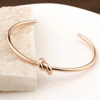 Minimalist knotted cuff bangle in 18k gold plated stainless steel jewelry.