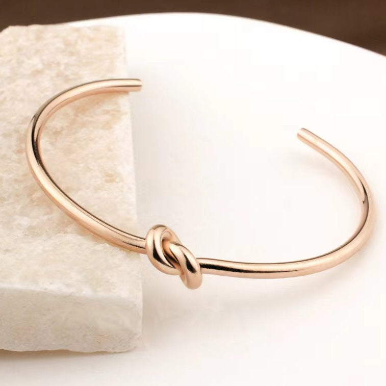 Minimalist knotted cuff bangle in 18k gold plated stainless steel jewelry.