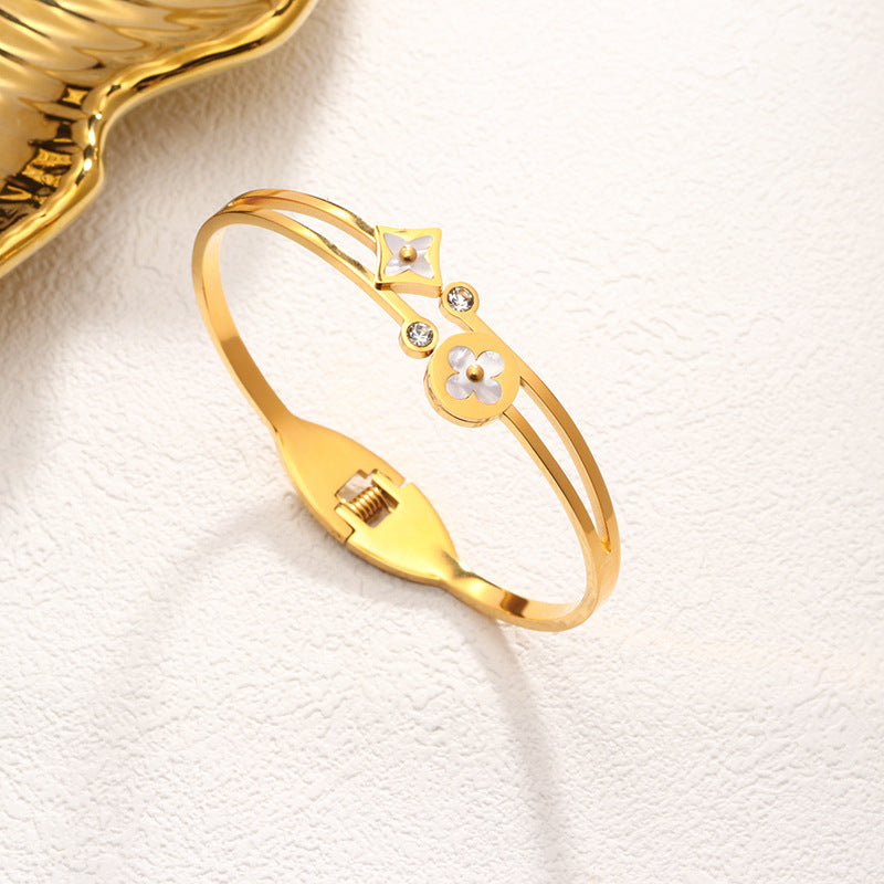 Mother of pearl clover station and crystal accent stainless steel jewelry bangle in waterproof 18k gold plated finish.