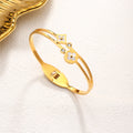 Mother of pearl clover station and crystal accent stainless steel jewelry bangle in waterproof 18k gold plated finish.