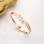 Mother of pearl clover station and crystal accent stainless steel jewelry bangle in waterproof 18k gold plated finish.