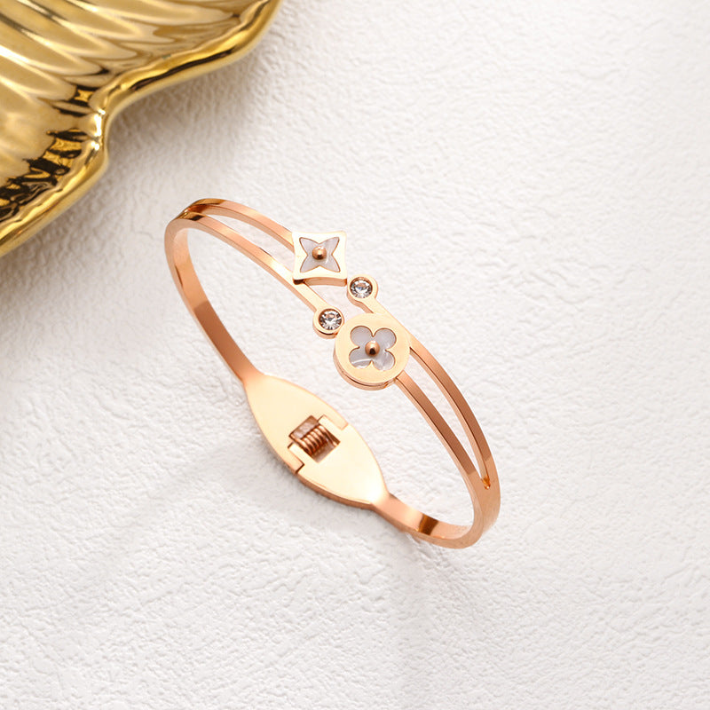 Mother of pearl clover station and crystal accent stainless steel jewelry bangle in waterproof 18k gold plated finish.