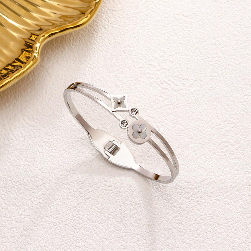 Mother of pearl clover station and crystal accent stainless steel jewelry bangle in waterproof 18k gold plated finish.
