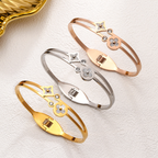 Mother of pearl clover station and crystal accent stainless steel jewelry bangle in waterproof 18k gold plated finish.