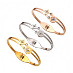 Mother of pearl clover station and crystal accent stainless steel jewelry bangle in waterproof 18k gold plated finish.