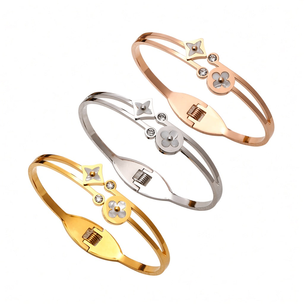 Mother of pearl clover station and crystal accent stainless steel jewelry bangle in waterproof 18k gold plated finish.