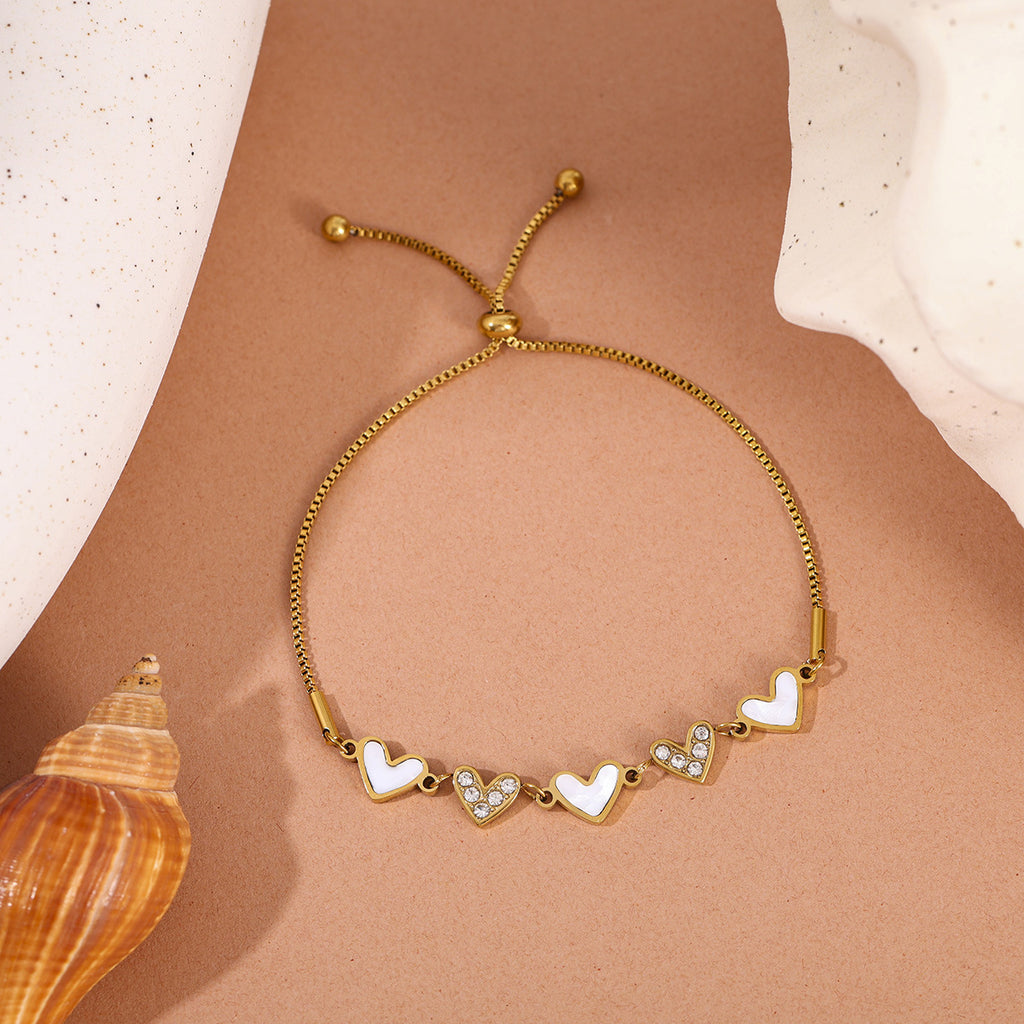 Mother of pearl shell heart stations and pave cubic zirconia CZ heart link slider box chain stainless steel jewelry bracelet in waterproof 18k gold plated finish.