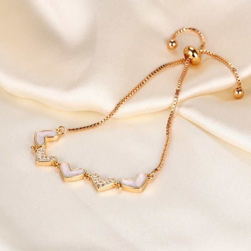 Mother of pearl shell heart stations and pave cubic zirconia CZ heart link slider box chain stainless steel jewelry bracelet in waterproof 18k gold plated finish.