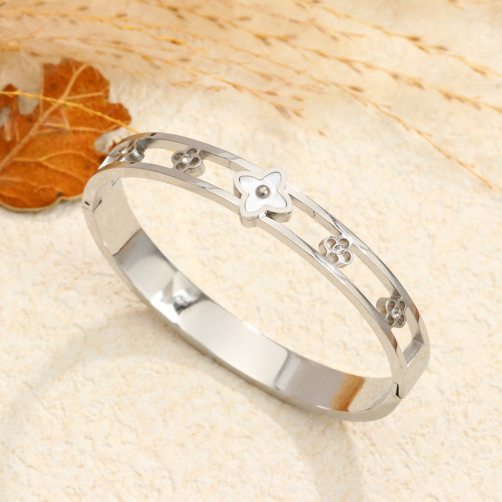 Mother of pearl monogram flower center motif and cut-out floral stations stainless steel jewelry bangle in waterproof 18k gold plated finish.