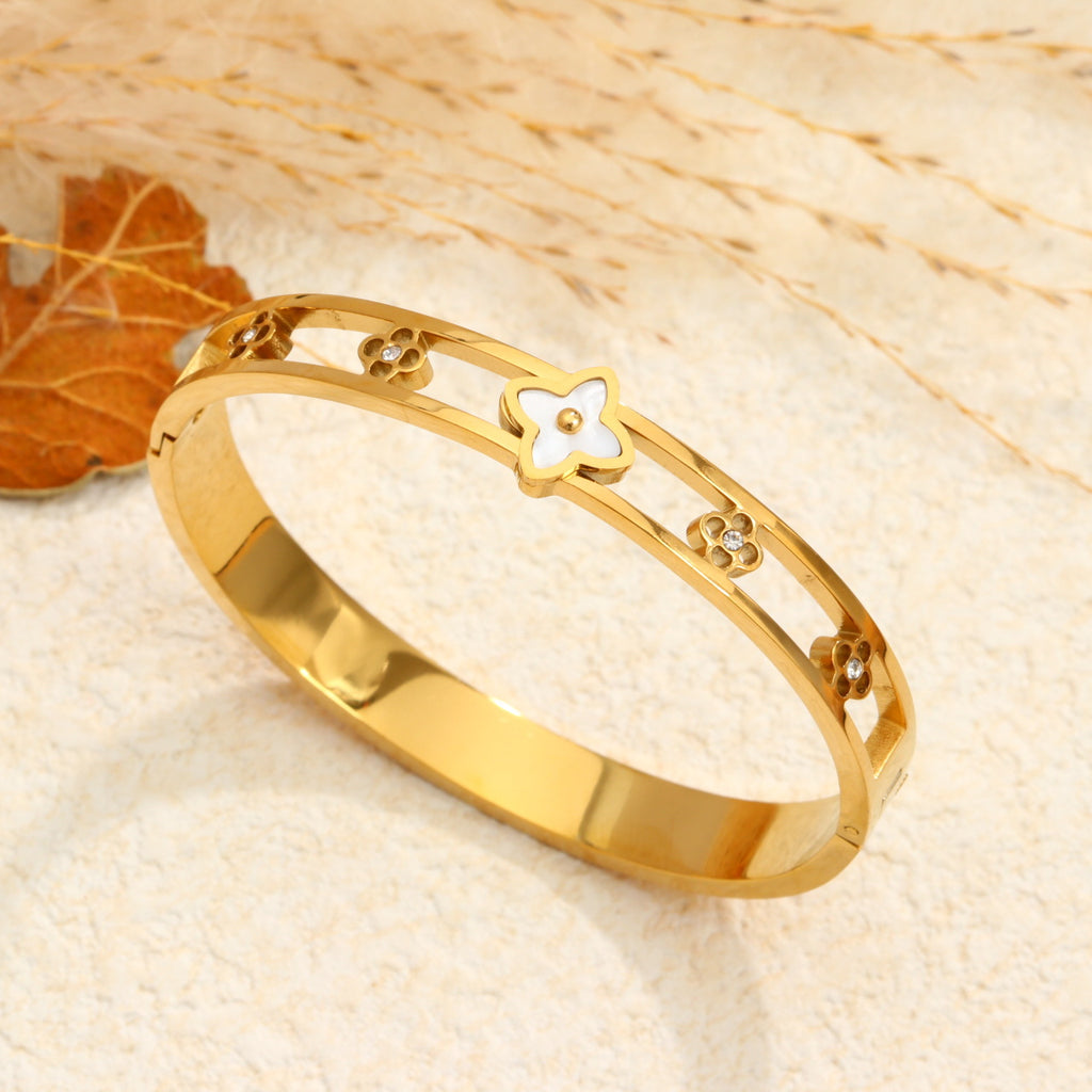 Mother of pearl monogram flower center motif and cut-out floral stations stainless steel jewelry bangle in waterproof 18k gold plated finish.