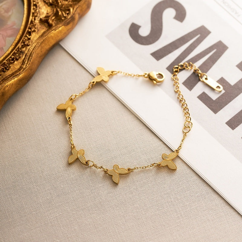 Textured butterfly charm stations fine link chain stainless steel jewelry bracelet in waterproof 18k gold plated finish.