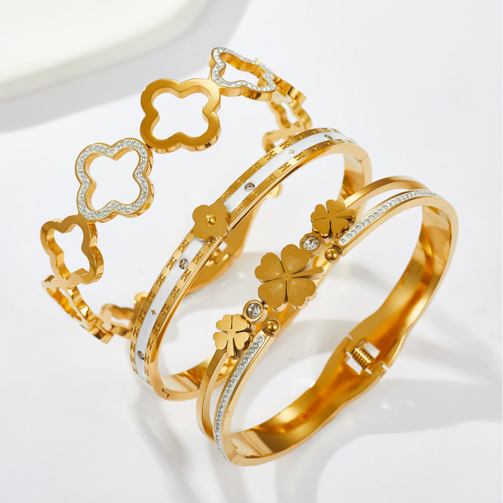 Multi four-leaf clover station and pave cubic zirconia accent stainless steel jewelry bangle in waterproof 18k gold plated finish.