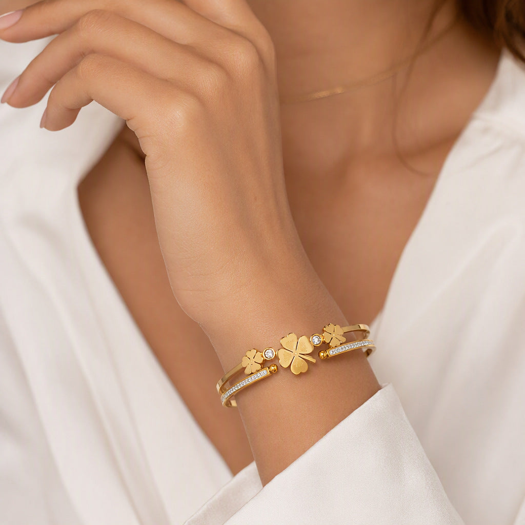 Multi four-leaf clover station and pave cubic zirconia accent stainless steel jewelry bangle in waterproof 18k gold plated finish.
