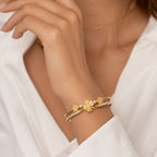 Multi four-leaf clover station and pave cubic zirconia accent stainless steel jewelry bangle in waterproof 18k gold plated finish.