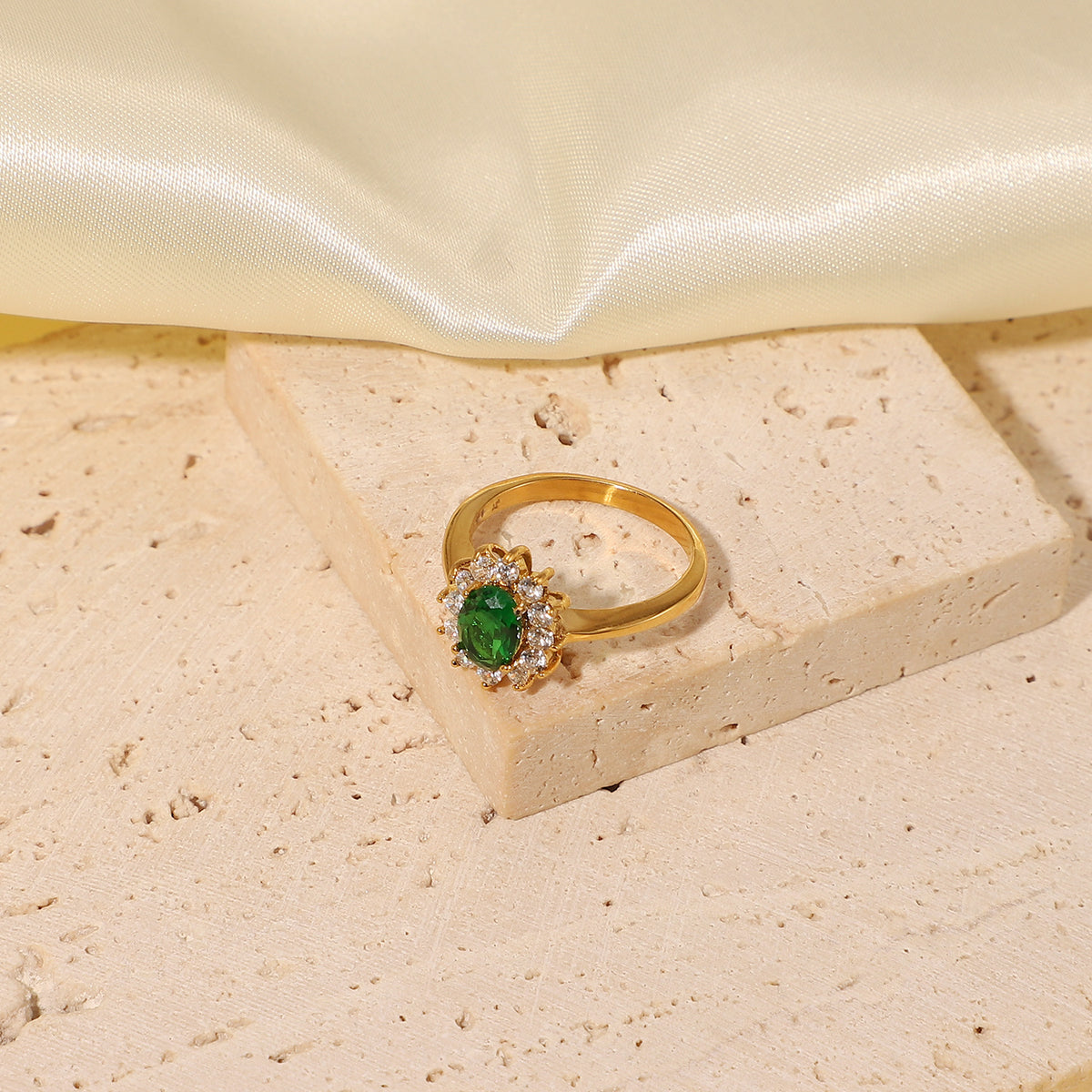 Oval emerald green cubic zirconia center stone framed by a sparkling clear cz crystal halo stainless steel jewelry ring in waterproof 18k gold plated finish.