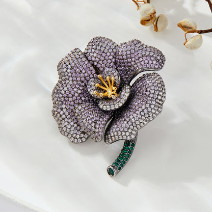 Elegant camellia brooch with purple gradient cubic zirconia petals, a golden stamen, and a green stem