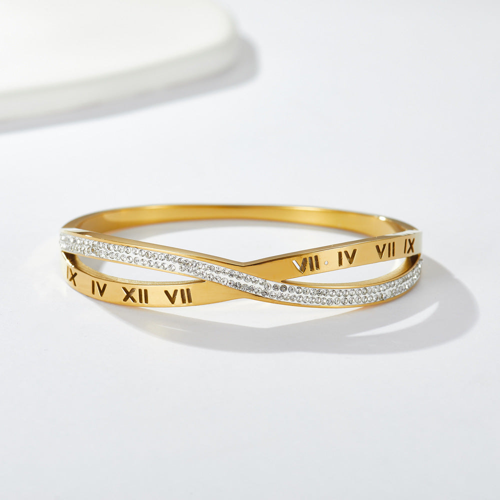 Engraved Roman numeral and pave cubic zirconia crossover stainless steel bangle bracelet jewelry in waterproof 18k gold plated finish.