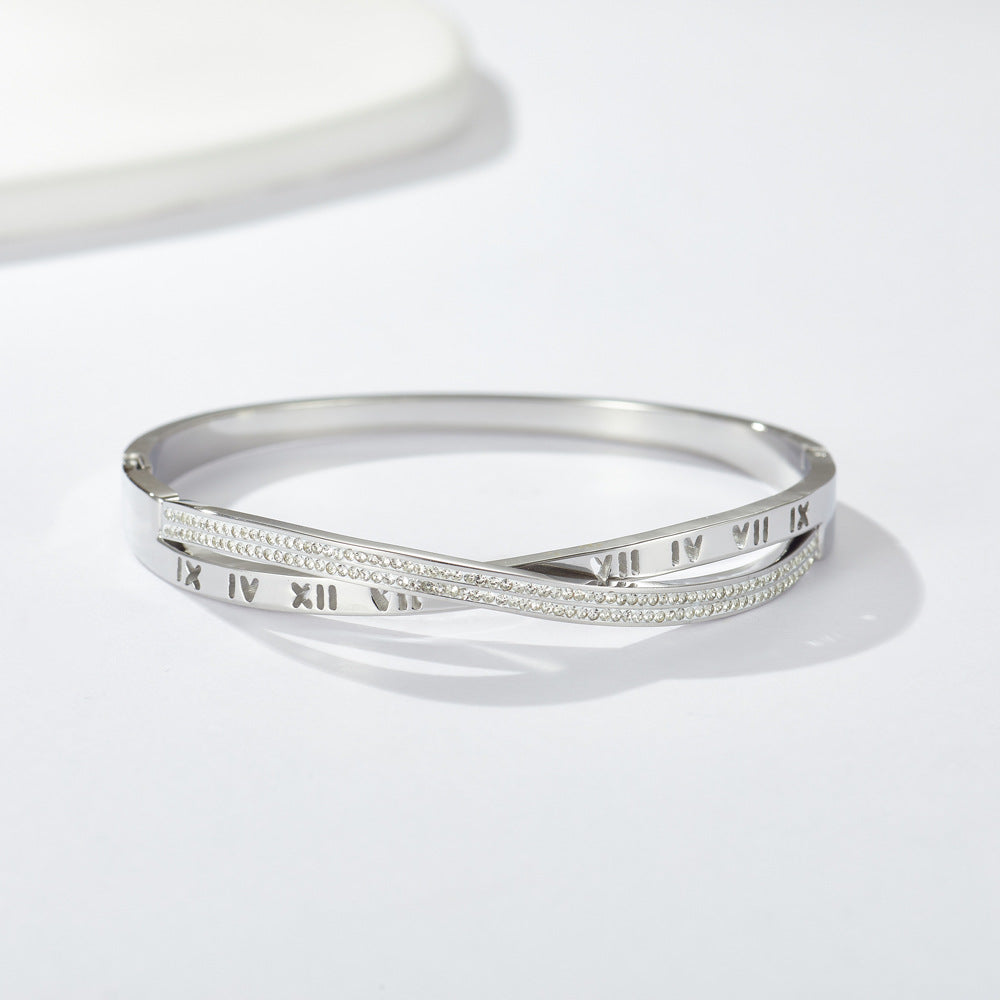 Engraved Roman numeral and pave cubic zirconia crossover stainless steel bangle bracelet jewelry in waterproof 18k gold plated finish.