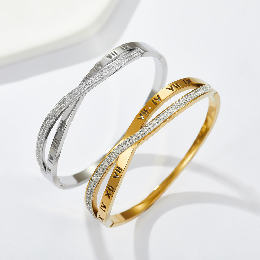 Engraved Roman numeral and pave cubic zirconia crossover stainless steel bangle bracelet jewelry in waterproof 18k gold plated finish.